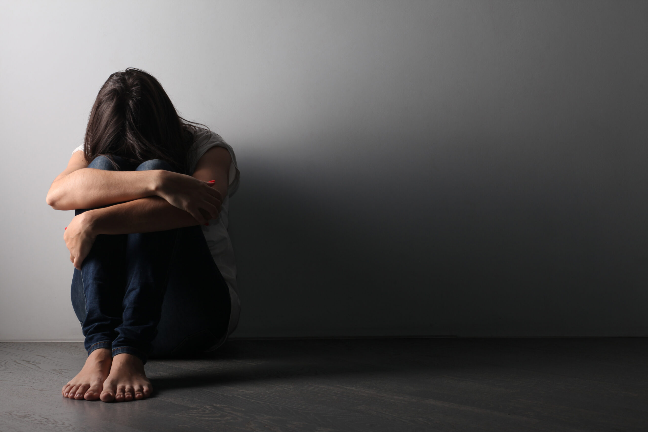 Woman sitting with head in arms. The mood is intended to represent feelings of depression, stress, despair.